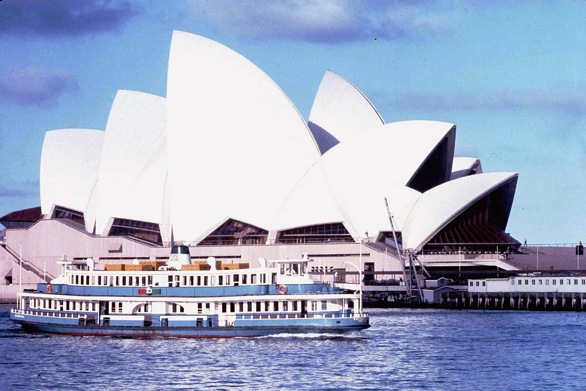 A blue and white Sydney ferry passing the newly opened Opera House in October 1973, with the white shells behind